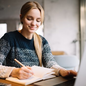 Junge Studentin sitzt am Laptop