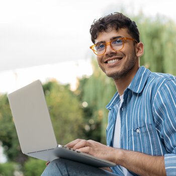 [Translate to Englisch:] Junger Mann mit Brille am Laptop